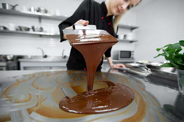 A chocolate maker tempering chocolate by hand