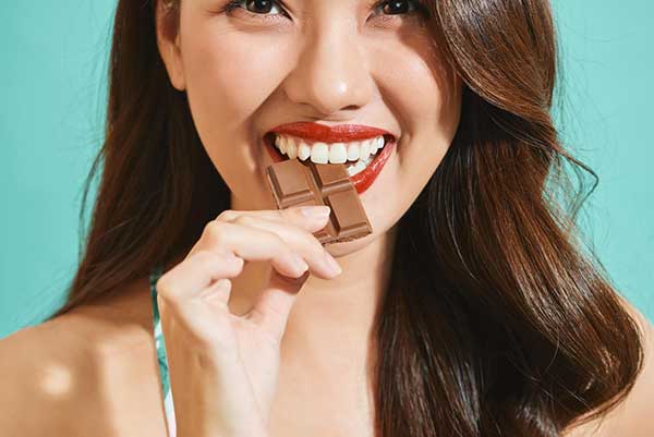 happy woman eating chocolate bar
