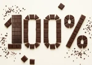 broken mr popples raw chocolate pieces spelling 100 percent with cocoa nibs on cream